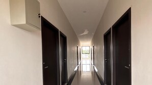Un pasillo largo y estrecho con puertas a ambos lados, que conduce a una habitación luminosa al final.