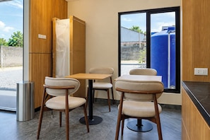 Cocina moderna con comedor, que incluye una mesa y cuatro sillas, un refrigerador y un ventanal con vistas a un depósito de agua azul exterior.