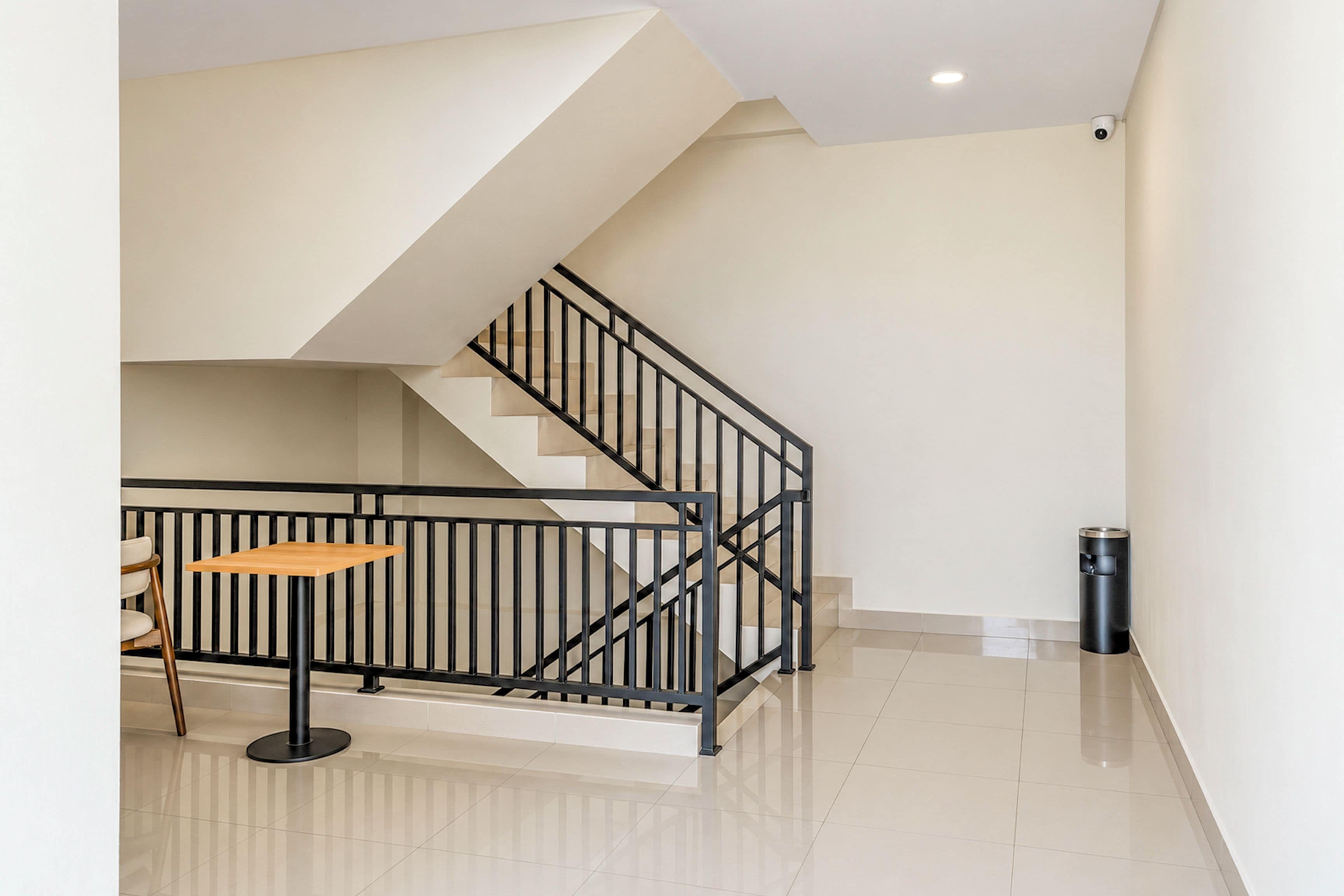 A modern interior with a staircase, a small table, and a trash bin.
