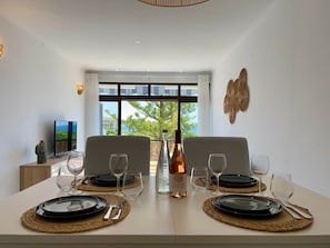 A dining area with two chairs, a table set for two, and a bottle of wine. - "Mar à Vista" Apartment (Olhos de Água)