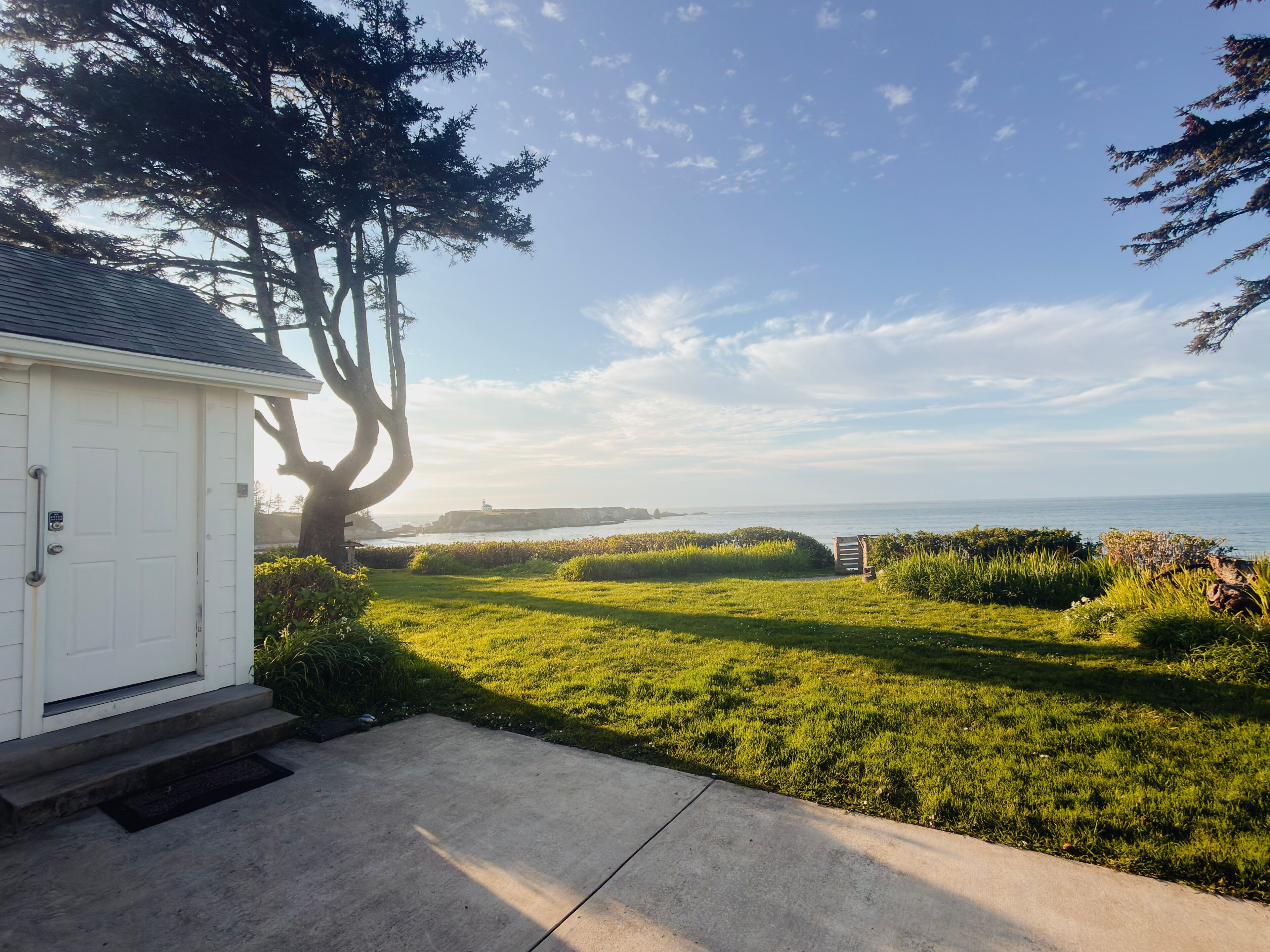A house with a front yard, a tree, and a view of the ocean.