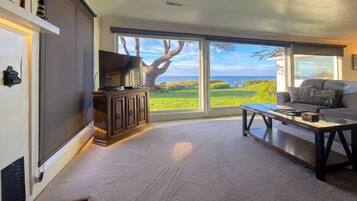 A living room with a large window, a television, a sofa, and a coffee table.