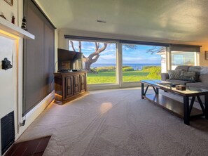 A living room with a large window, a television, a sofa, and a coffee table.