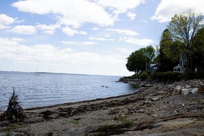 Un paisaje costero con costa rocosa, un muelle y un velero en el agua.