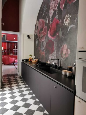 A modern kitchen with a black countertop, a sink, and a large floral mural on the wall. - Charming 2-beDROOMS  apartment with AC in Napoli center in spanish quarter (Napoli)