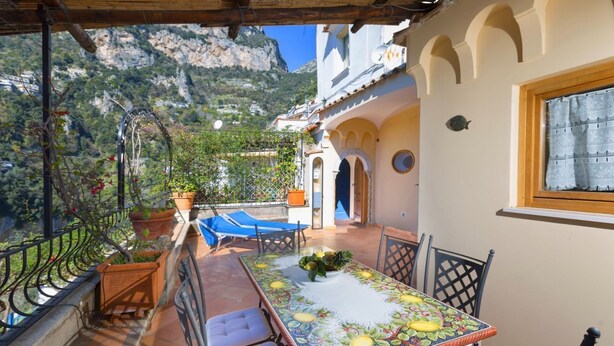 Une terrasse avec une table, des chaises et des plantes en pot.