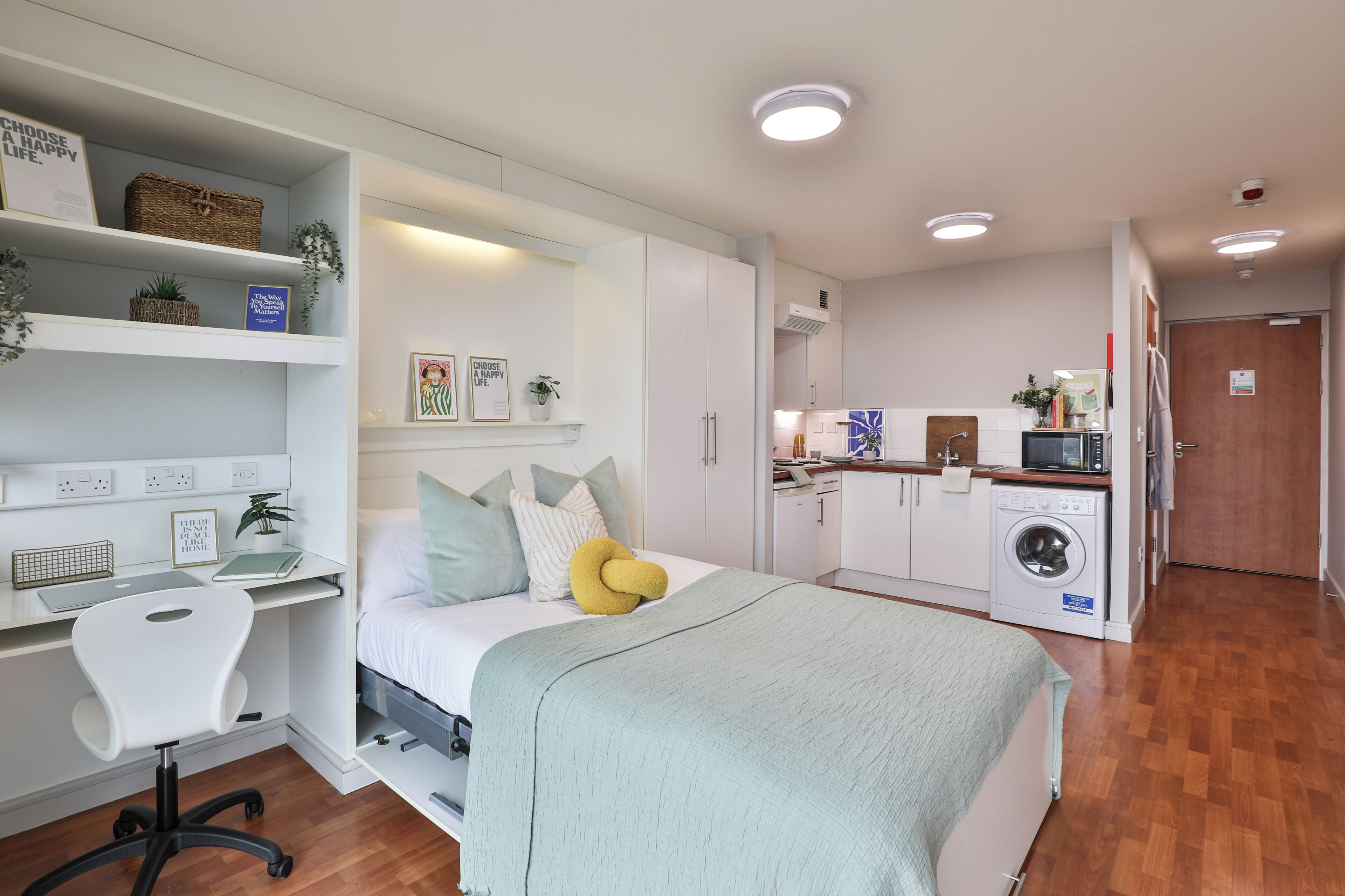 Quarto compacto com cama, mesa de cabeceira, cadeira e armário embutido.