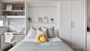Quarto com cama, escrivaninha, cadeira e guarda-roupa.