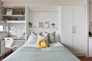 A bedroom with a bed, a desk, a chair, and a wardrobe. - Student Only Maritime Studios (Falmouth)