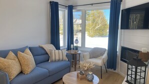 Un salon comprenant un canapé, un fauteuil, une table basse et une cheminée.
