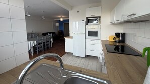 A compact kitchen with a sink, microwave, oven, and a dining area with a table and chairs. - ✨ Charming T3 in Le Touquet - View of dunes & beach on foot 🌊 ✨ (Paris)