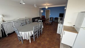 A dining area with a table and chairs, a sofa, a TV, and a kitchen area with a refrigerator. - ✨ Charming T3 in Le Touquet - View of dunes & beach on foot 🌊 ✨ (Paris)