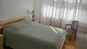 A bedroom with a bed, a chair, a lamp, and a window with curtains. - ✨ Charming T3 in Le Touquet - View of dunes & beach on foot 🌊 ✨ (Paris)