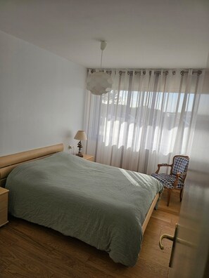 A bedroom with a bed, a chair, a lamp, and a window with curtains. - ✨ Charming T3 in Le Touquet - View of dunes & beach on foot 🌊 ✨ (Paris)