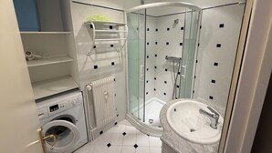 A bathroom with a glass-enclosed shower, a built-in washing machine, a radiator, and a sink with a marble countertop. - ✨ Charming T3 in Le Touquet - View of dunes & beach on foot 🌊 ✨ (Paris)