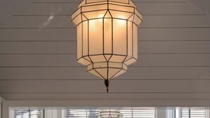A kitchen with a central island, a pendant light fixture, and a view through large windows. - Wedged Inn (Dunmore Town)