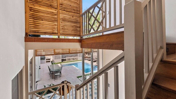 A wooden staircase leading to a balcony with a pool view. - Wedged Inn (Dunmore Town)