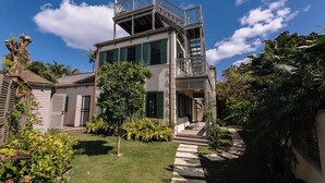 A two-story house with a balcony, a staircase, and a garden. - Wedged Inn (Dunmore Town)