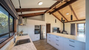 Une cuisine moderne dotée d’un grand îlot central, d’appareils électroménagers en acier inoxydable et d’un plafond en bois.