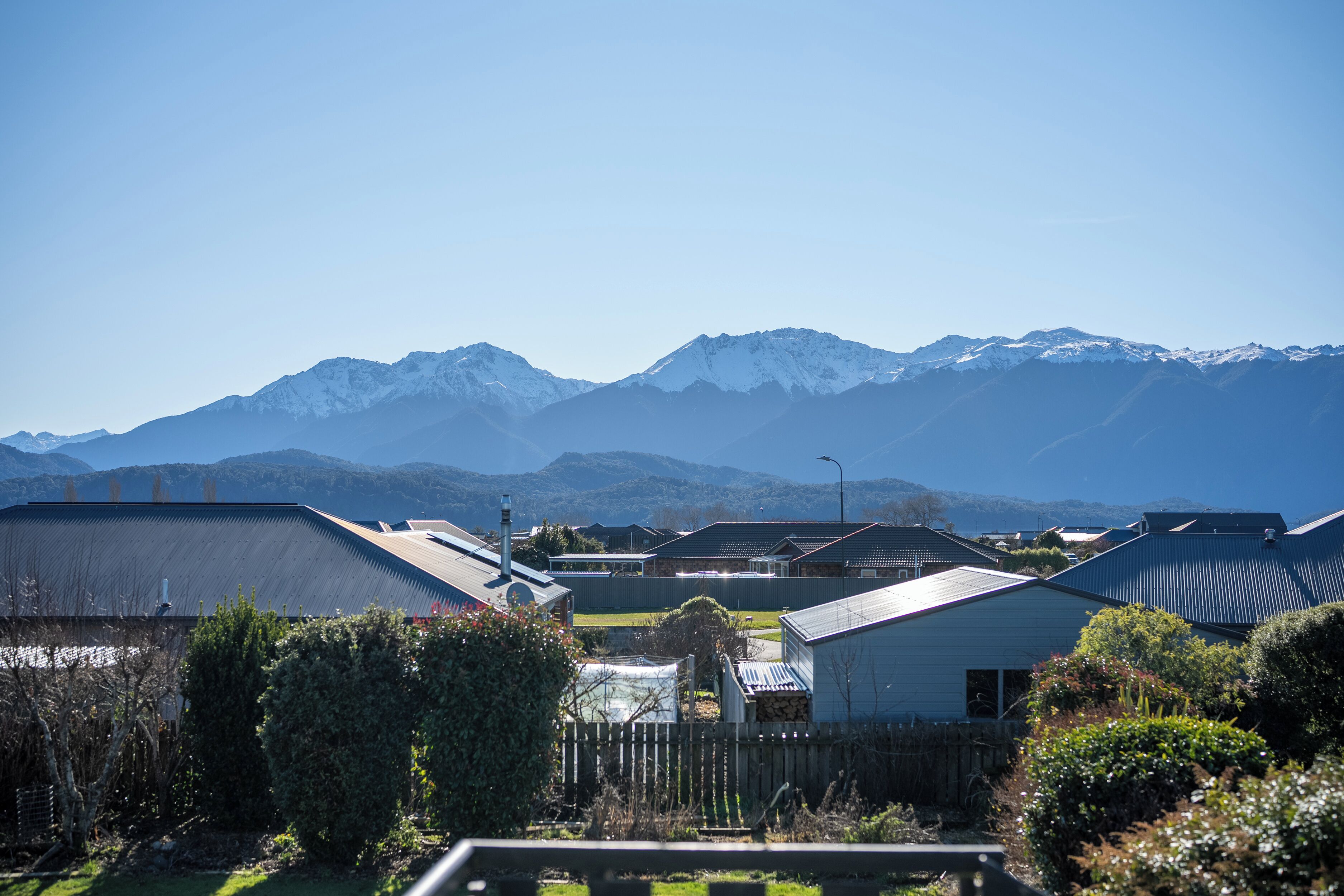 Un quartier résidentiel avec des maisons, une clôture et des montagnes en arrière-plan.