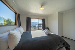 Ein Hotelzimmer mit einem großen Bett, Blick ins Freie und einer Deckenleuchte.