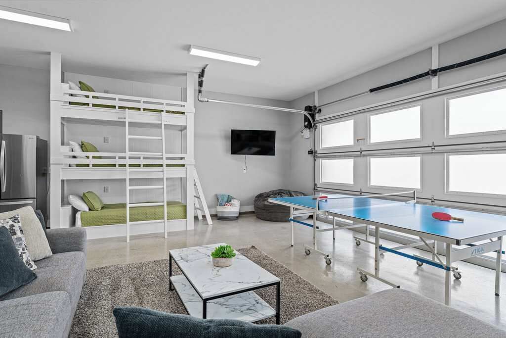 A modern room with bunk beds, a ping pong table, a sofa, and a TV.