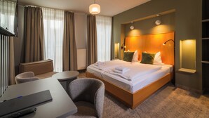 A hotel room with a bed, a desk, a chair, a lamp, and curtains. - Erbenhof (Weimar)