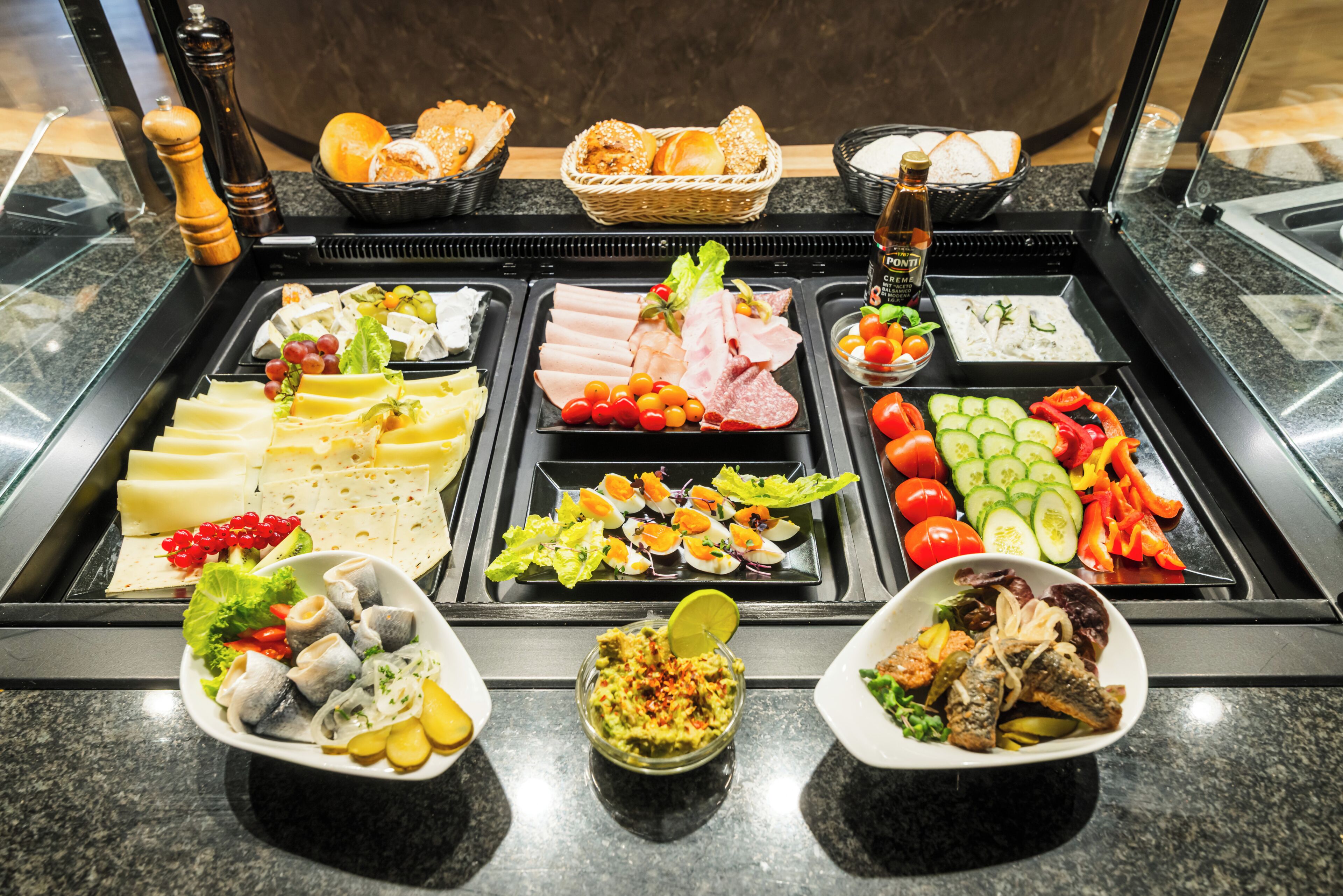 Ein reichhaltiges Buffet mit einer Auswahl an Speisen, darunter Fleisch, Käse und Gemüse.