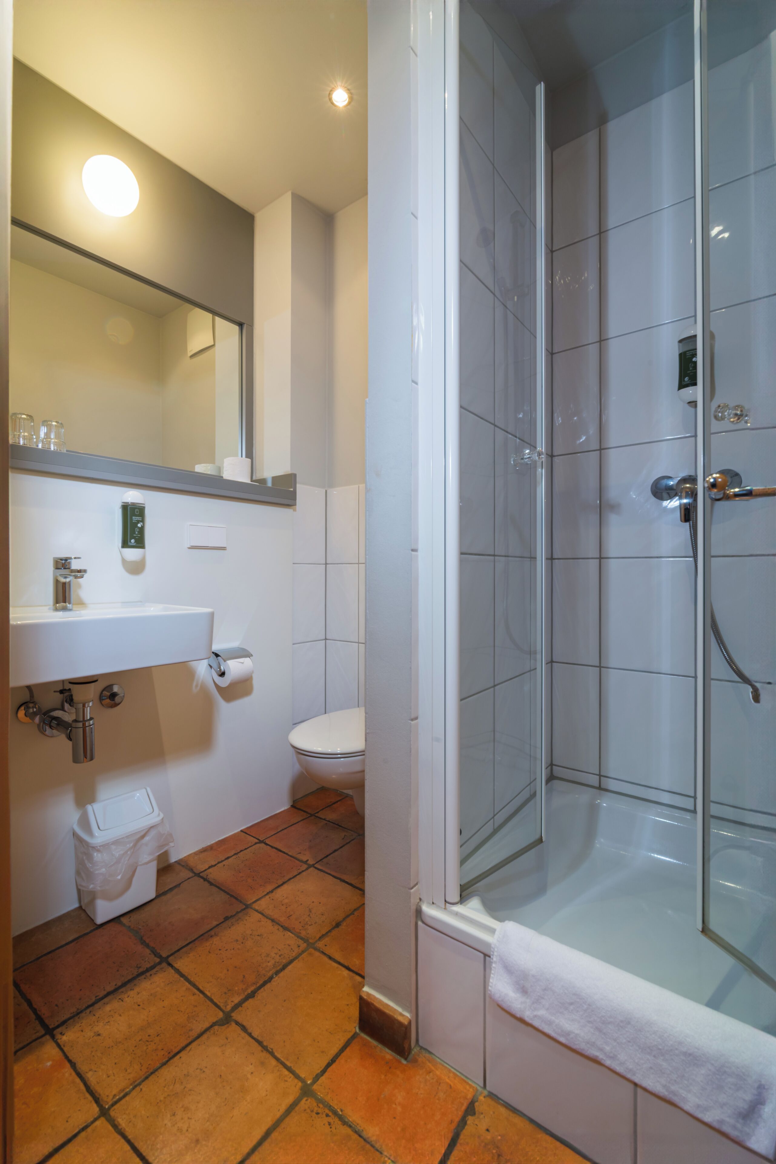 Un baño con ducha de vidrio, lavamanos, inodoro y espejo.