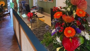 A reception desk with a floral arrangement, a computer, and a chair. - Erbenhof (Weimar)