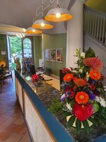 Mostrador de recepción con un arreglo floral, una computadora y una silla.