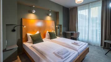 Une chambre d’hôtel avec deux lits, un bureau, une chaise et une grande fenêtre avec des rideaux.