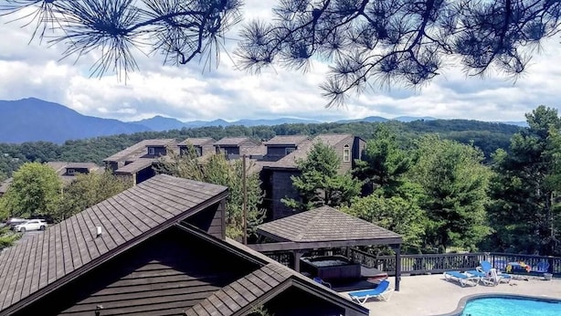 Un resort con varias edificaciones, una piscina y montañas al fondo.