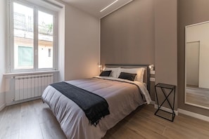 Une chambre à coucher avec un lit, une fenêtre, un radiateur et une porte.