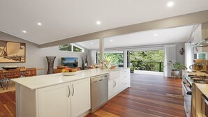 Een moderne keuken met een centraal eiland, houten vloer en uitzicht op groen.