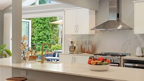 A modern kitchen with white cabinets, a stainless steel range hood, and a marble backsplash. - Arcadia Cottage - spacious, stylish Highlands stay for families and groups near Bowral (Bowral)