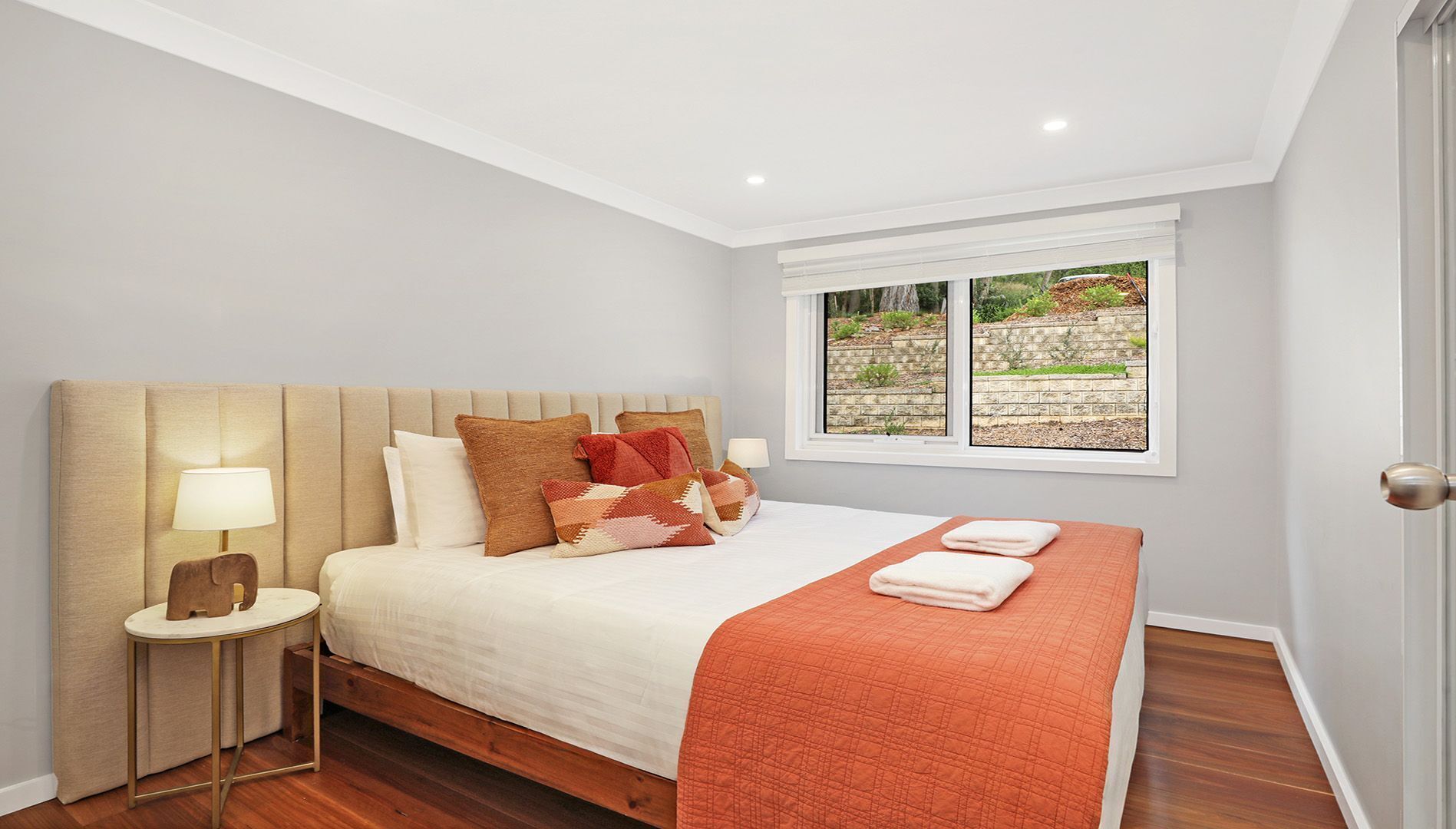 Un dormitorio con cama, lámpara de noche, ventana y vistas al exterior.