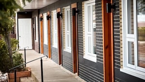 File di camere d'albergo con ingressi individuali, un portico e una piccola area esterna con delle scale.