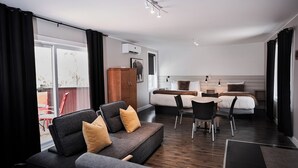 Una camera d'albergo moderna con divano, letto, scrivania e zona pranzo.