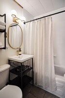 A bathroom with a toilet, sink, mirror, and shower curtain.