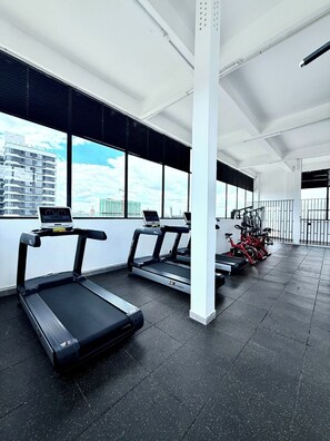 Een moderne sportschool met loopbanden, hometrainers en een roeimachine.