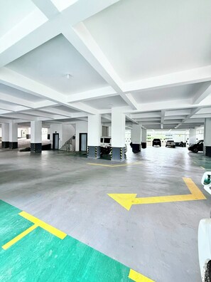 Ruime parkeergarage met duidelijke pijlen op de vloer, betonnen pilaren en een hoge ruimte met zichtbare balken.