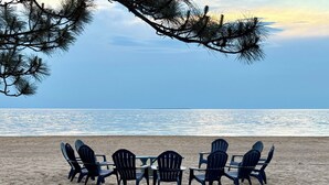 Ranta, jolla on rivi Adirondack-tyylisiä puutarhatuoleja ja pöytä, ja josta avautuu näkymä valtamerelle.