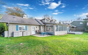 A two-story house with a covered patio, a fenced backyard, and a small deck.