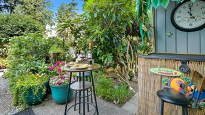 Un jardin avec une table, des chaises et une horloge accrochée au mur.