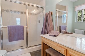 A bathroom with a shower, toilet, and vanity with towels. - Paradise Pines (Big Bear Lake)