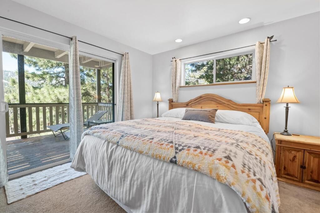 A bedroom with a bed, two bedside lamps, a window, and a balcony.