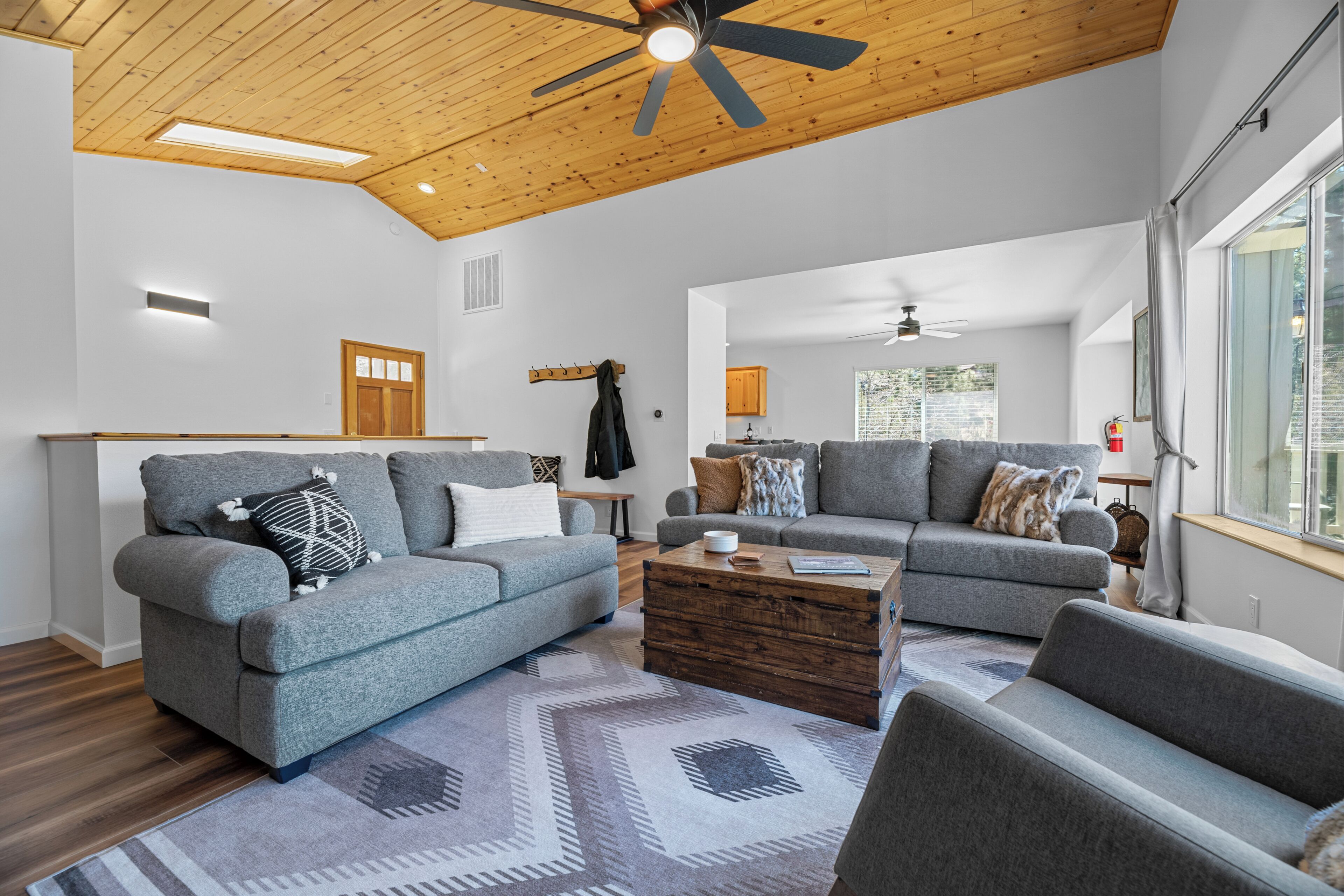 A modern living room with grey sofas, a wooden coffee table, and a ceiling fan.