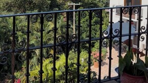 A balcony with a view of the sea, surrounded by greenery and a white building. - Casa Romantica - Spectacular 2 BR villa in PV near beach- private pool/hot tub (Puerto Vallarta)