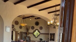 Sisätilat, joihin kuuluu ruokailutila, keittiö sekä oleskelutila, jossa on tuoli ja pöytä.